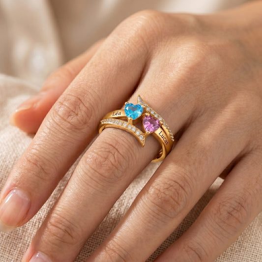 Bague cœur personnalisée portée, finition or, prénoms Léa et Lucas, pierres cœur bleue et rose