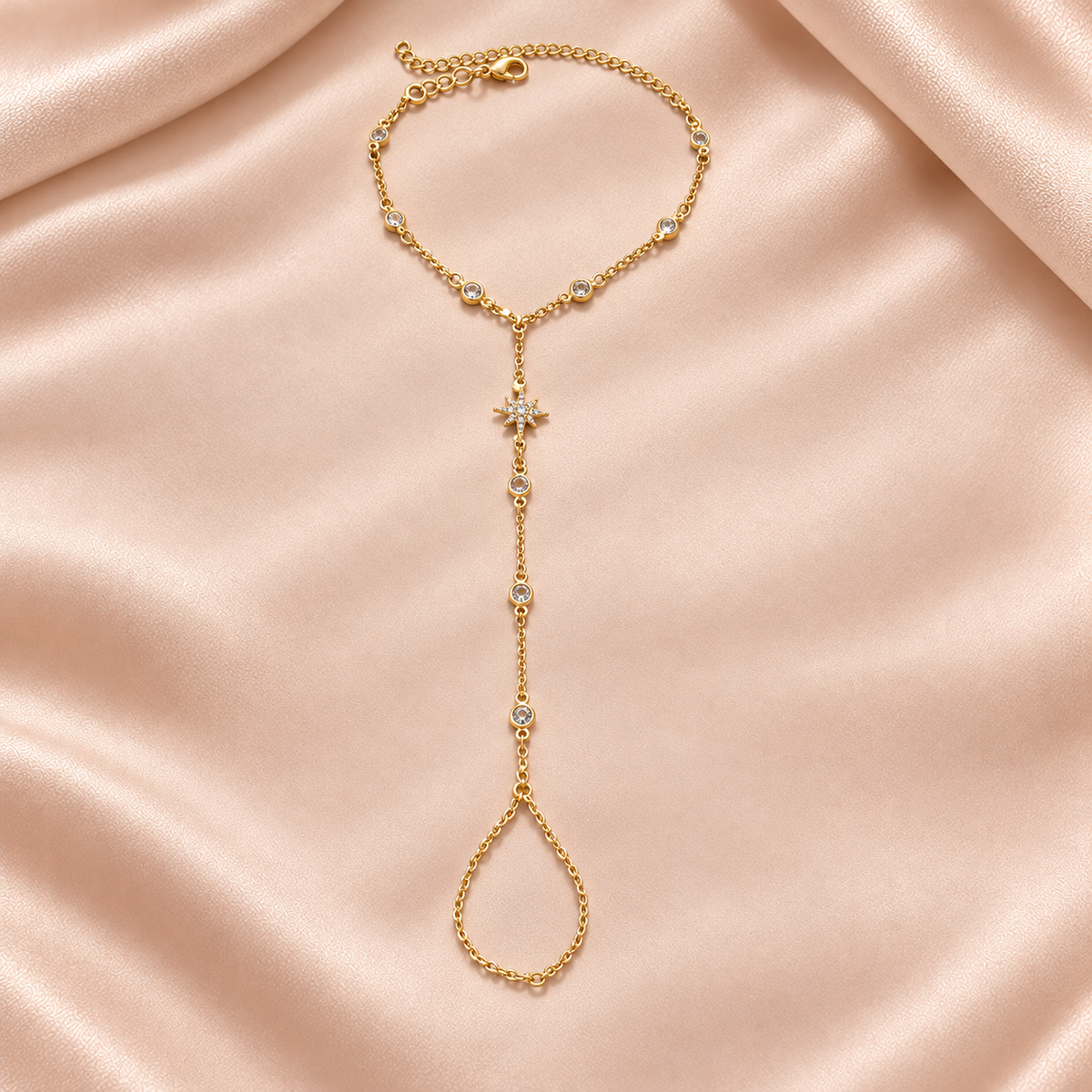 Chaîne de main étoile dorée sur satin beige rosé